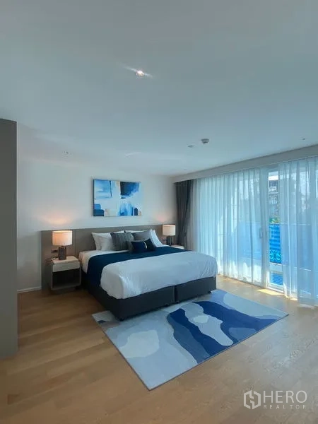 公寓 出租在Watthana, Bangkok - 大床卧室以蓝色为点缀，推门连接带纱帘的阳台。