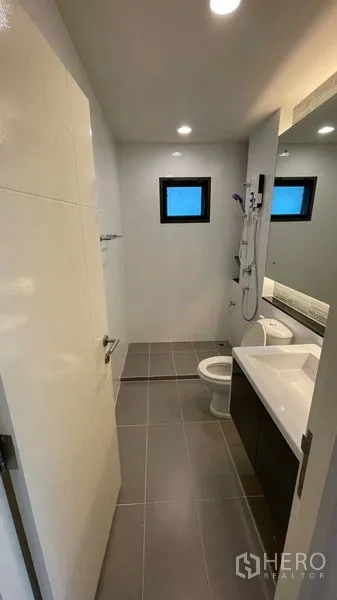 Detached House for rent in Bang Kapi, Bangkok - Modern bathroom with shower unit, toilet, vanity and small frosted window.