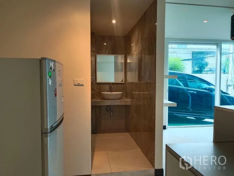 Retail Space for rent - Shop interior leading to modern restroom and glass entrance, refrigerator to the side.