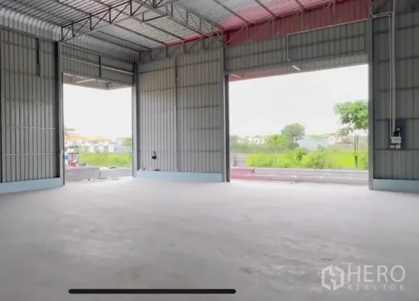 Warehouse for rent in Lam Luk Ka, Pathum Thani - Spacious warehouse interior with high steel roof, wide openings and smooth concrete floor facing greenery.