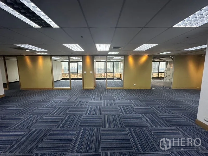 办公空间 出租在Khlong Toei, Bangkok - 蓝色方块地毯的大型工位区，多扇玻璃门