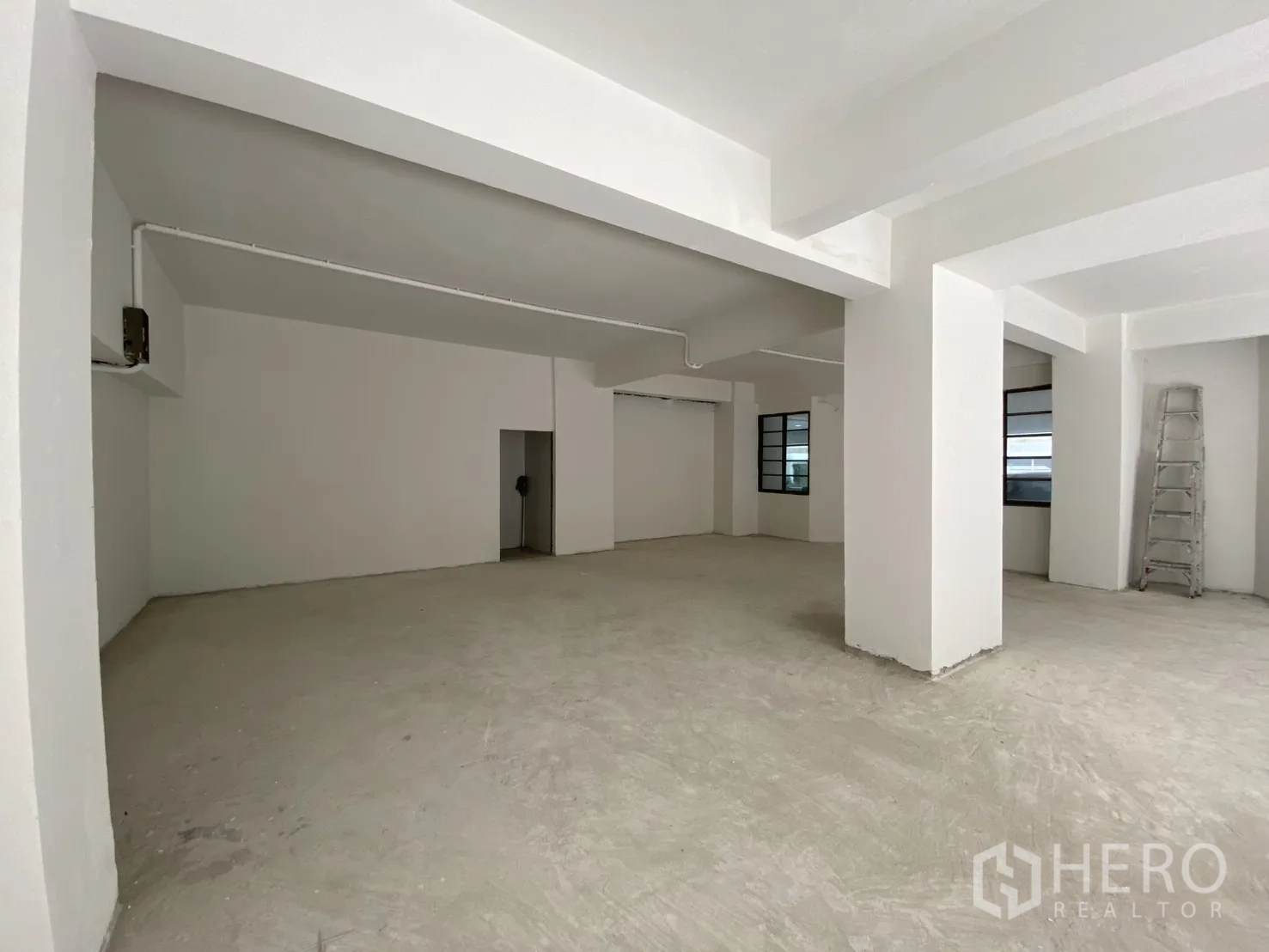 พื้นที่ขายปลีก for rent in Watthana, Bangkok - ห้องเปิดโล่ง เสาสีขาว พื้นคอนกรีตขัดหยาบ พร้อมประตูหลังบ้าน.