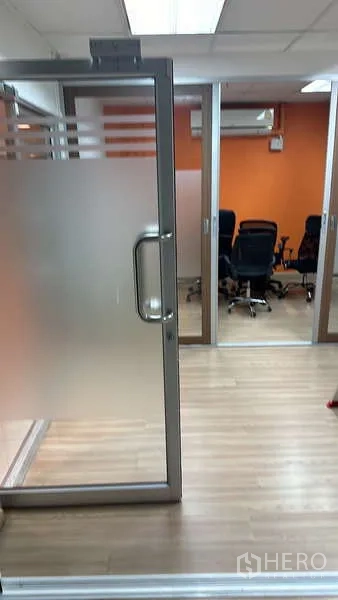 办公空间 出租 - 磨砂玻璃门通往会议室，橙色特色墙与座椅。