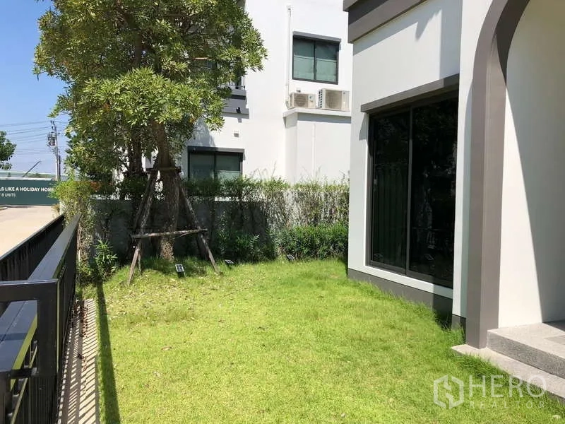 บ้าน ขายในBang Sao Thong, Samut Prakan - สวนหน้าบ้านด้านข้าง มีต้นไม้ สนามหญ้า และรั้วเหล็ก