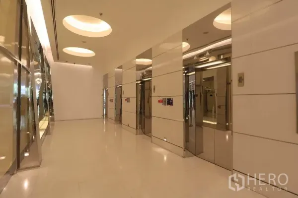 Office Space for rent in Bang Rak, Bangkok - Bright elevator lobby with multiple stainless steel lifts and circular ceiling lights