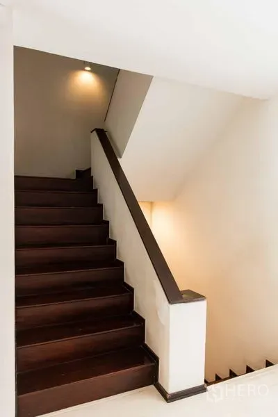 Townhouse for sale - Staircase with dark wood steps and soft wall lighting.