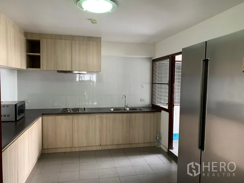 公寓 出租或出售在Watthana, Bangkok - 厨房配L形木柜、灶台、水槽与对开门大冰箱。