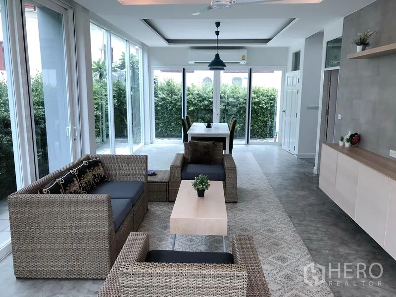 บ้าน ให้เช่าหรือขายในHuai Khwang, Bangkok - พื้นที่นั่งเล่นและทานอาหารแบบเปิดโล่ง รับแสงดี มีโซฟาหวายและกระจกเต็มบานมองสวน