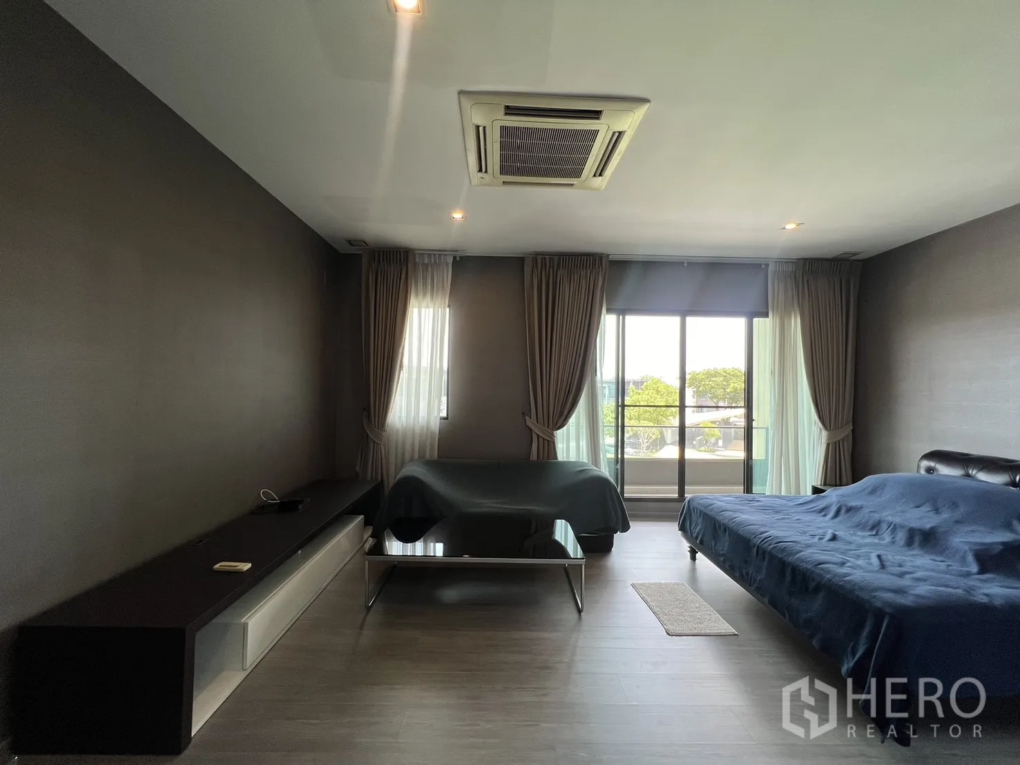 Townhouse for rent in Lat Phrao, Bangkok - Large master bedroom with sliding doors to balcony and full-height windows.