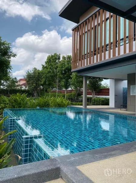 联排别墅 出租在Prawet, Bangkok - 住区会所的蓝色马赛克室外泳池与绿化景观。