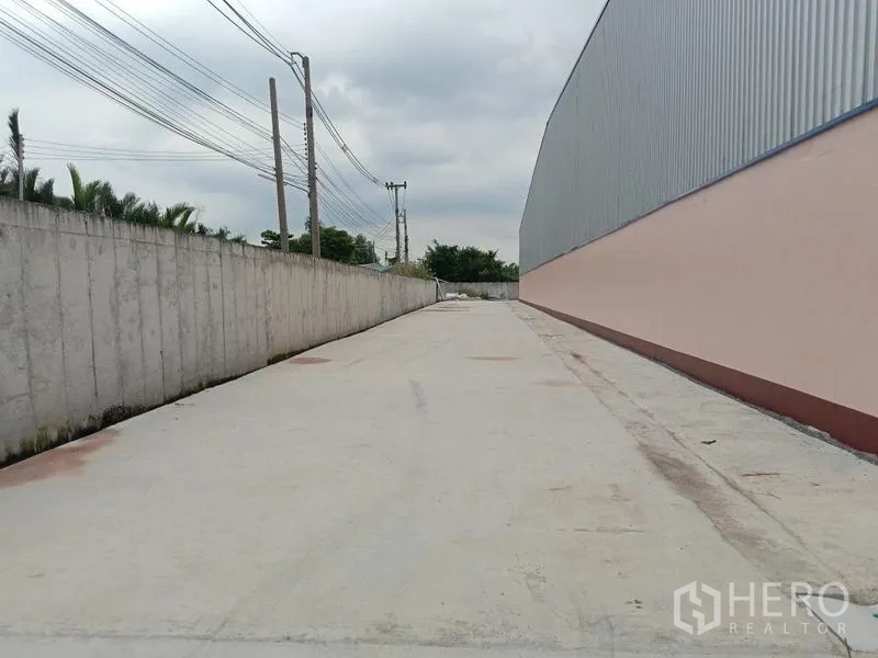 โรงงาน ให้เช่าในBan Phaeo, Samut Sakhon - ทางวิ่งด้านข้างตามแนวกำแพงรั้วของโรงงาน เหมาะสำหรับการวนรถบรรทุกและขนถ่ายสินค้า