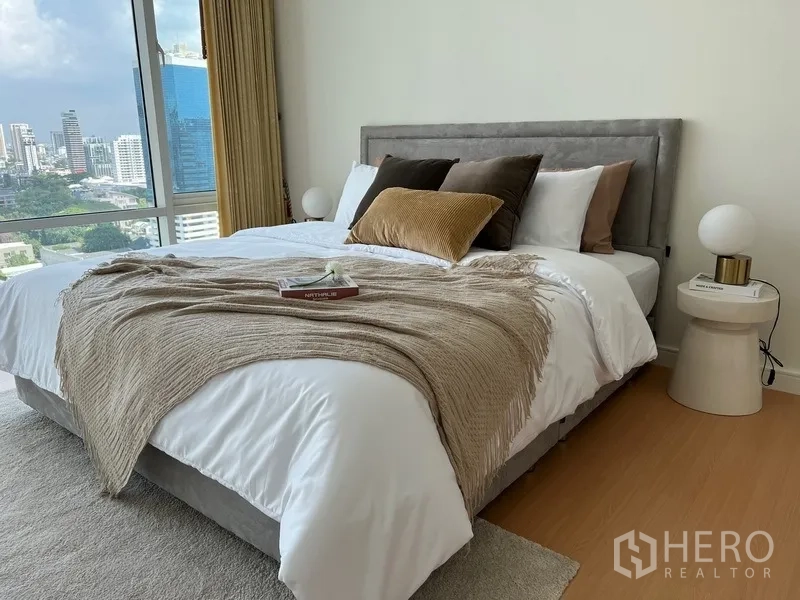 公寓 出租在Watthana, Bangkok - 卧室软装温暖，抱枕与披毯搭配，临近大幅窗景。