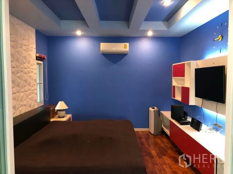 Detached House for sale in Wang Thonglang, Bangkok - Bedroom with blue accent wall, recessed ceiling and media console.