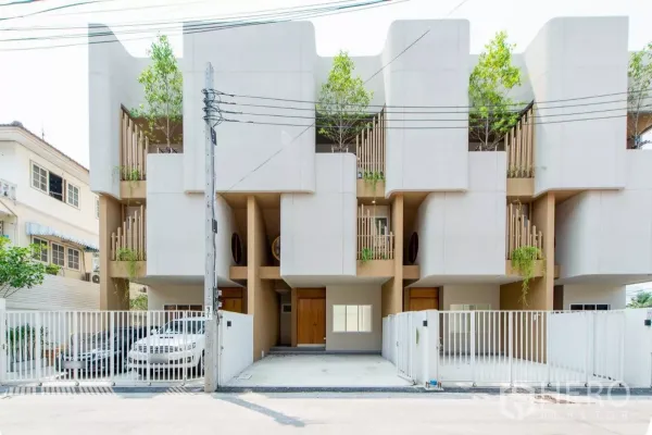 Townhouse for sale in Lat Phrao, Bangkok - Modern three-storey townhouse facade with sculpted concrete, private gates and balcony greenery in Lat Phrao.