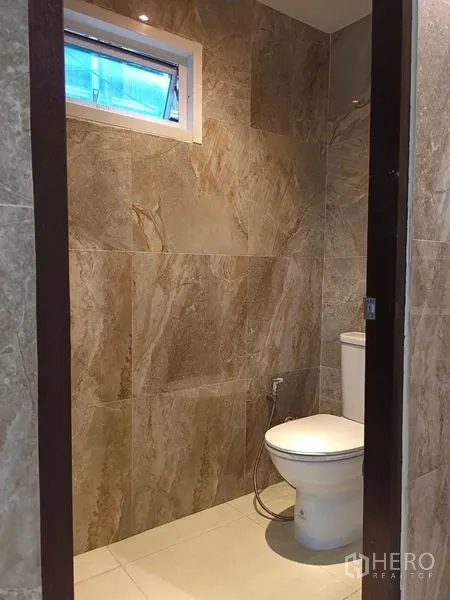 Retail Space for rent - Separate toilet room with small window and handheld bidet in tiled finish.