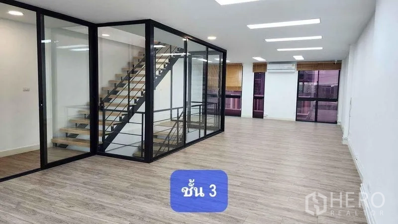 Townhouse for rent in Bueng Kum, Bangkok - Tall entry hall with glossy tile floor and floating wooden staircase leading to a mezzanine.