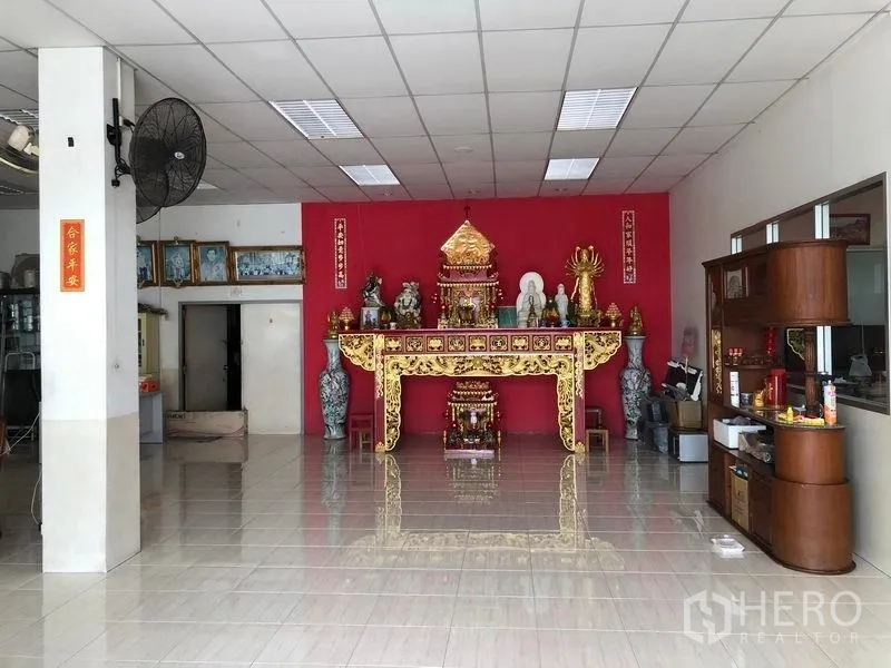 Factory for rent or sale in Lam Luk Ka, Pathum Thani - Interior hall featuring a decorative altar against a red accent wall.