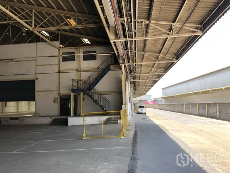 货栈 出租在Mueang Samut Prakan, Samut Prakan - 带顶装卸平台，金属楼梯通往夹层办公室，卡车通行通道宽敞。