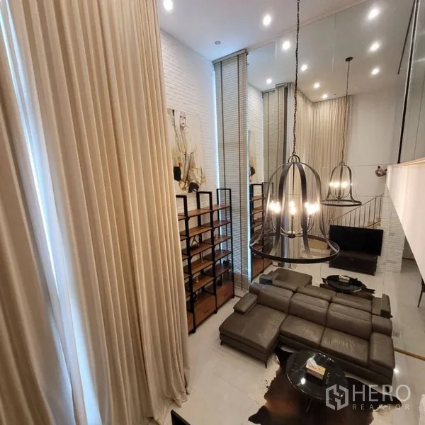 公寓 出租在Khlong Toei, Bangkok - 挑高客厅，落地窗帘、皮沙发与现代吊灯。