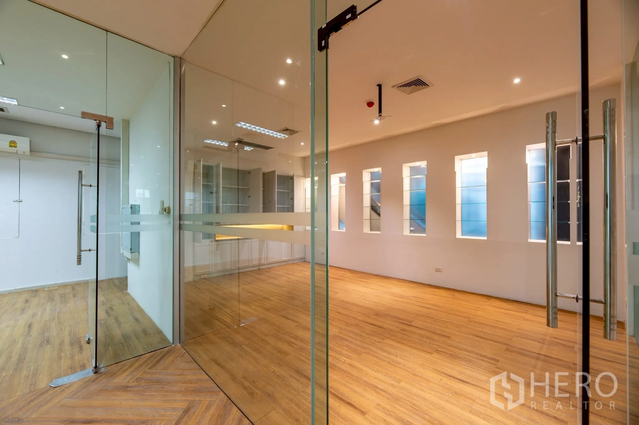 Office Space for rent in Wang Thonglang, Bangkok - Glass-partitioned private office with built-in cabinets and wood floors.