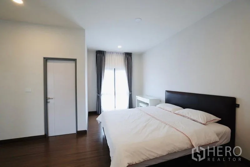 独立式住宅 出租在Bang Phli, Samut Prakan - 卧室配大床、书桌与通阳台的玻璃门。