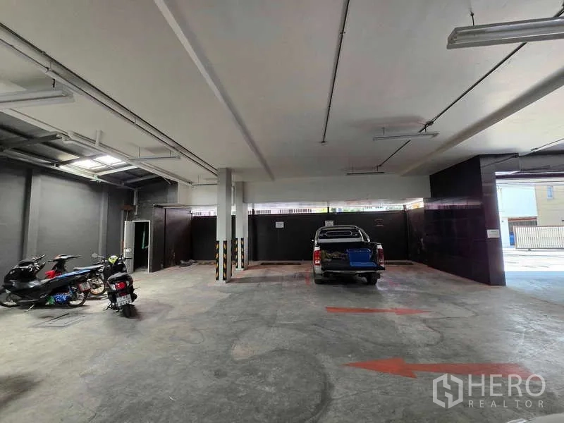 Retail Space for rent in Khlong Toei, Bangkok - Covered ground-floor parking and loading area with concrete floor, ceiling lights, motorcycles and a pickup truck.