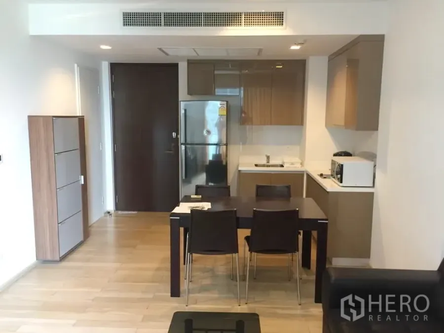 公寓 出租在Khlong Toei, Bangkok - 开放式厨房与餐区，亮面橱柜、不锈钢冰箱和四人餐桌的现代公寓。