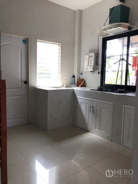 บ้าน ขายในLam Luk Ka, Pathum Thani - ห้องครัวที่สองมีหน้าต่าง เตา และตู้สีขาว