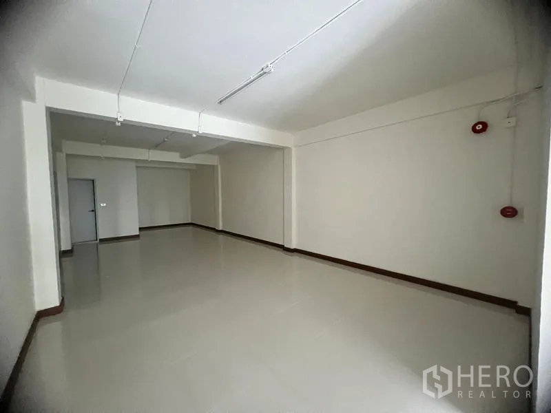 Shophouse for rent in Khlong Toei, Bangkok - Bright open-plan shophouse interior with glossy tile floors, white walls and ceiling strip lights.