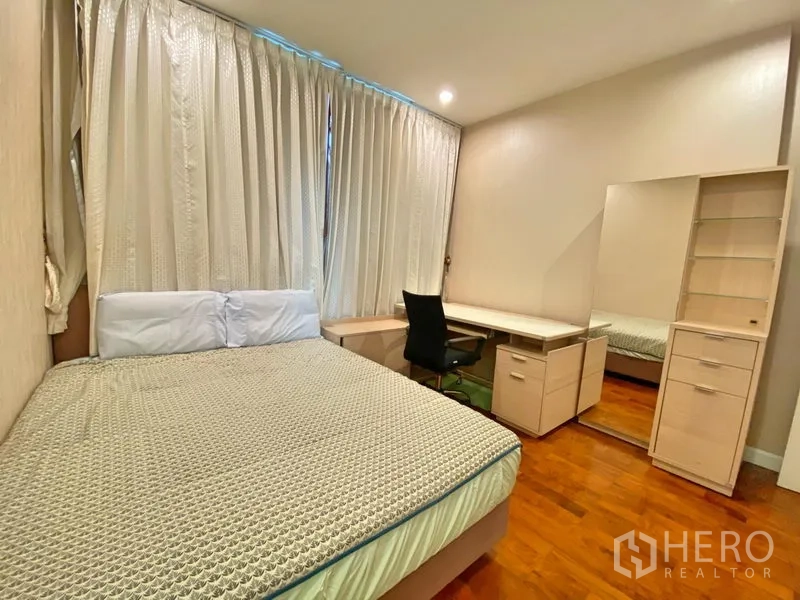 Condominium for rent in Khlong Toei, Bangkok - Second bedroom with built-in desk, shelving, mirror and curtained window.