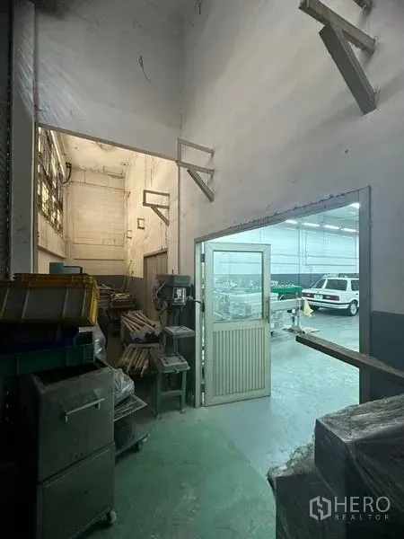 Factory for rent or sale in Khlong Luang, Pathum Thani - Service corridor and doorway leading to the main factory floor with tall walls.