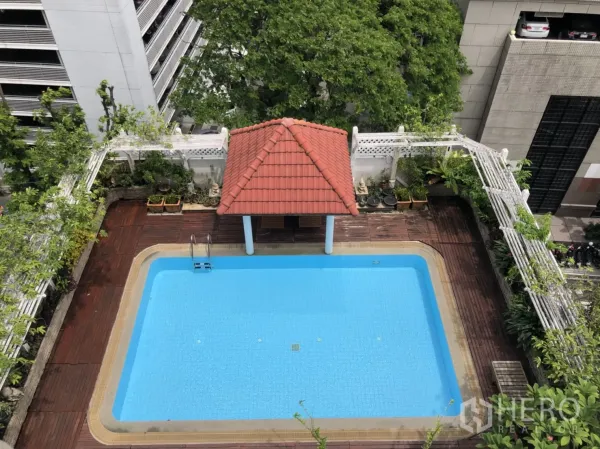 Apartment for rent in Bang Rak, Bangkok - Rooftop outdoor swimming pool with red-tile pavilion and wooden deck surrounded by city greenery.