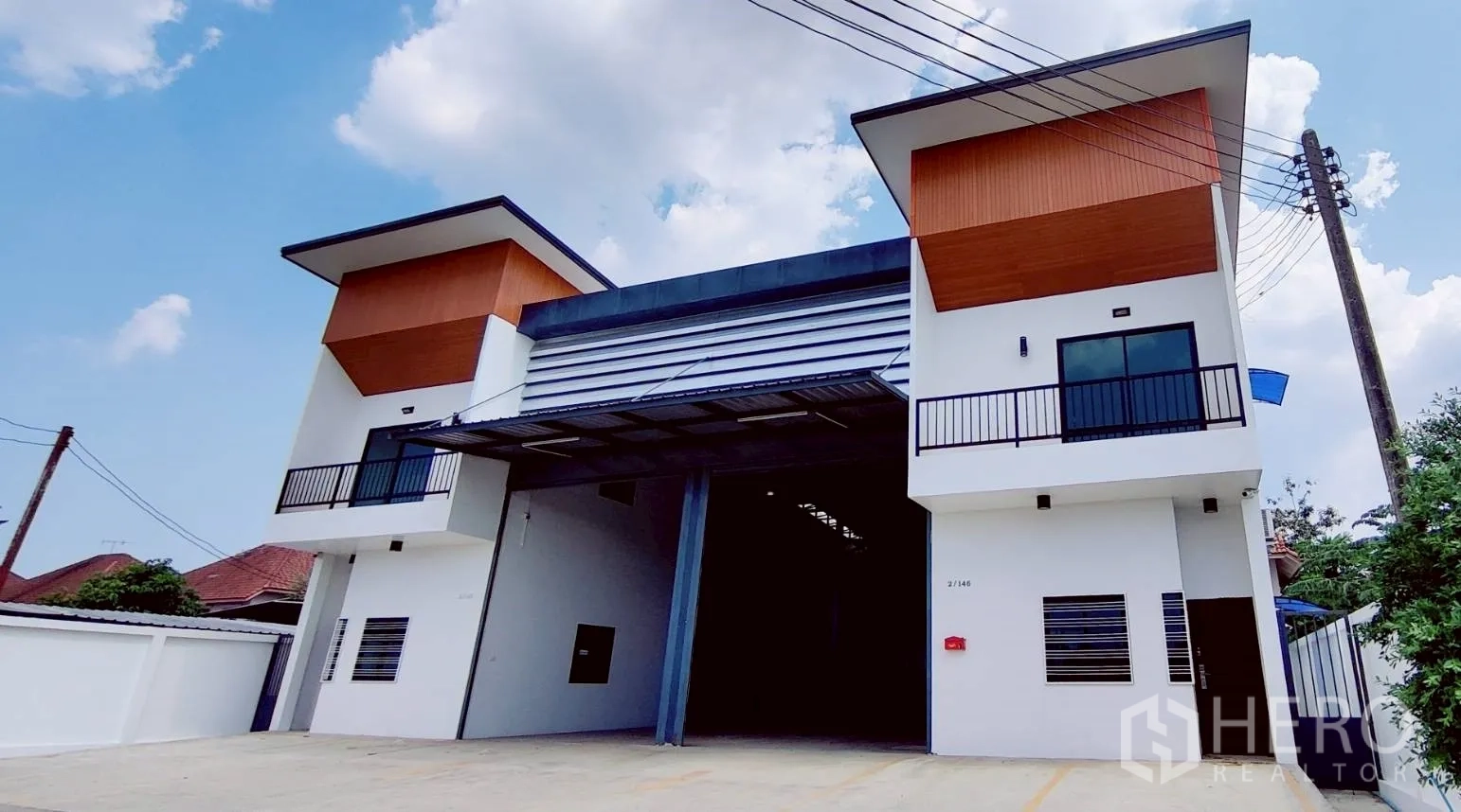 Warehouse for rent in Lam Luk Ka, Pathum Thani - Modern twin‑unit warehouse facade with wide motorized roller door and upper offices in Lam Luk Ka.