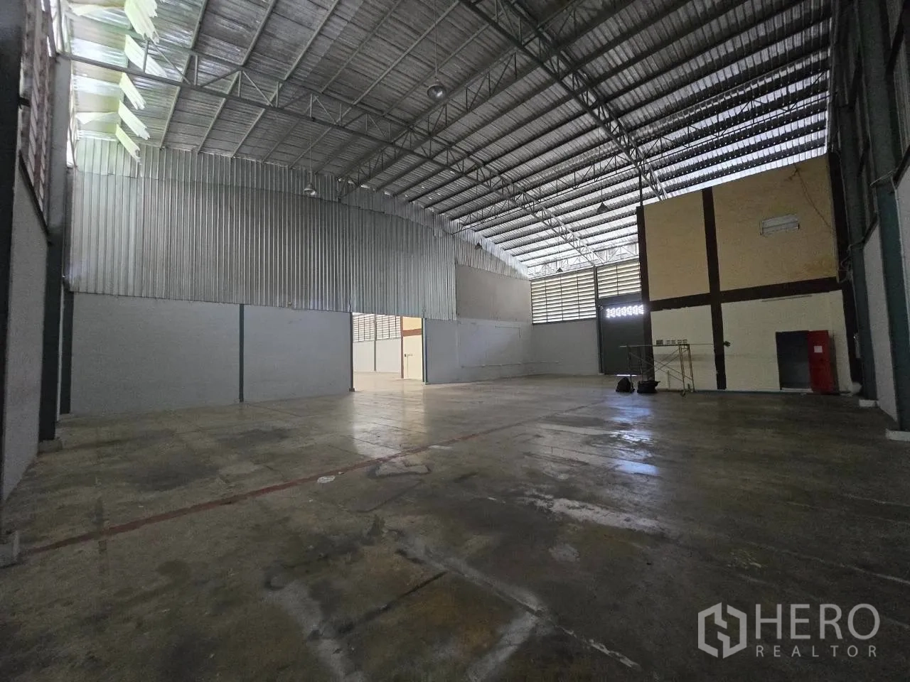 Warehouse for rent or sale in Mueang Samut Sakhon, Samut Sakhon - Spacious warehouse interior with a high steel truss roof, ventilated panels, and concrete flooring.