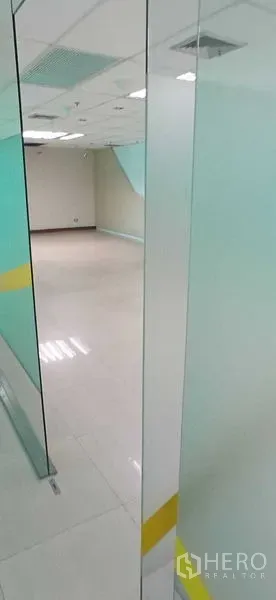 办公空间 出租在Huai Khwang, Bangkok - 通过透明玻璃门看到的空置办公室，地砖与天花灯。