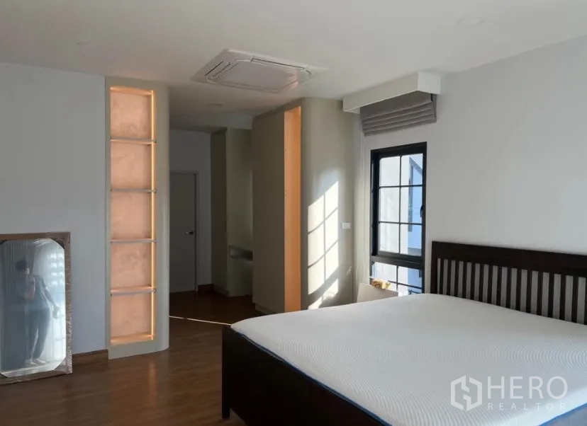 独栋房屋 for rent in Bang Phli, Samut Prakan - 主卧采光充足，木地板、深色床架、窗户、吊顶嵌入式空调与灯光装饰墙面。