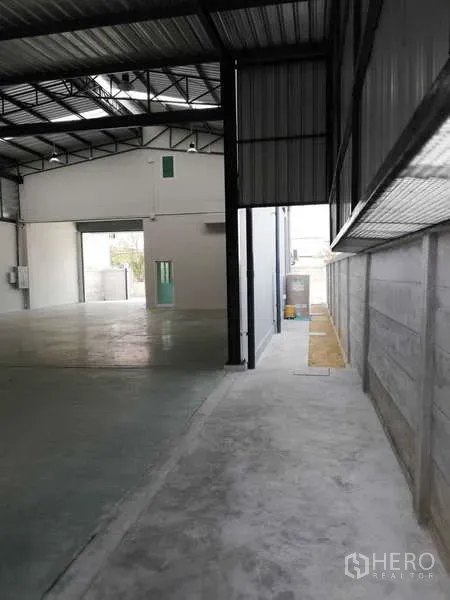Factory for rent or sale in Ban Phaeo, Samut Sakhon - Side aisle along warehouse wall with ventilation panels leading toward the rear