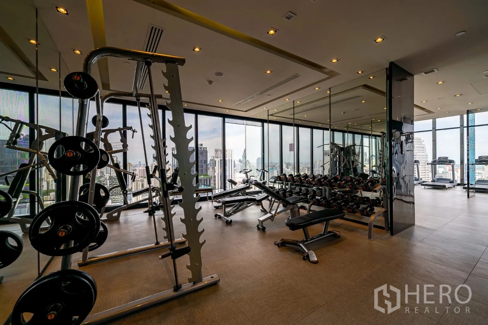 Condominium for rent in Watthana, Bangkok - Gym with free weights and glass walls showcasing the city view.