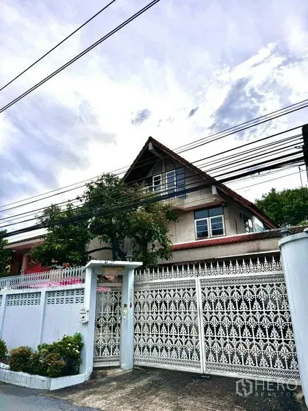独立式住宅 出售在Yan Nawa, Bangkok - 街侧视角的独栋住宅，雕花白色围栏与斜屋顶。