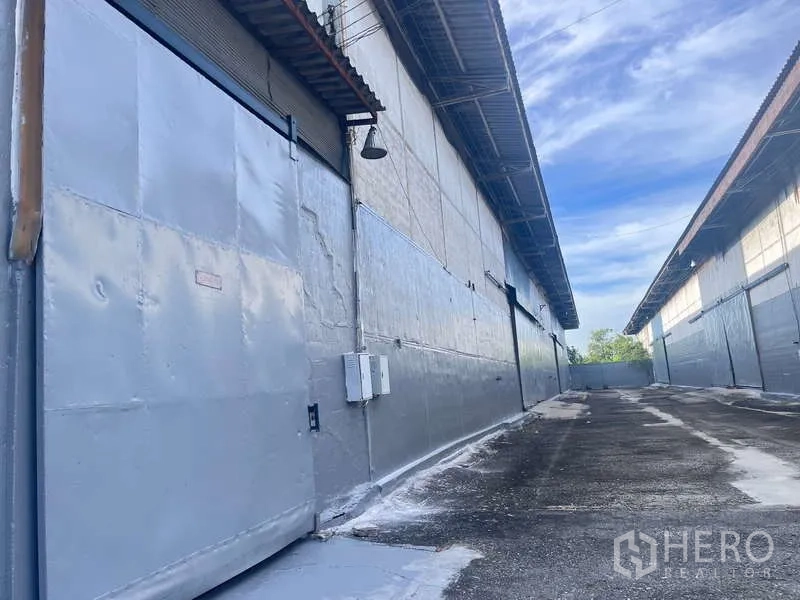 Factory for rent in Bang Pakong, Chachoengsao - Close-up of warehouse roller shutter door, electrical panels and access lane.