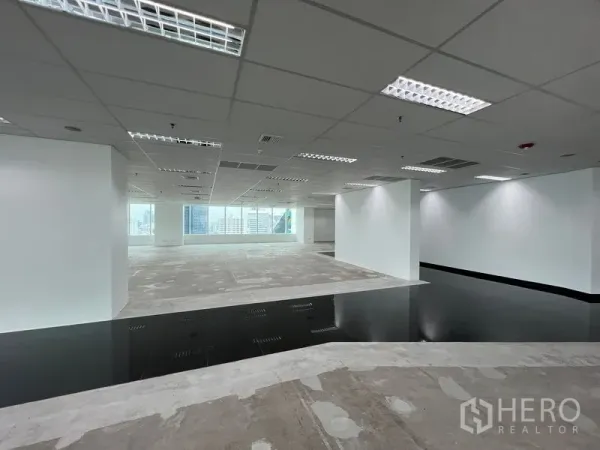 สำนักงาน ให้เช่า - โซนทำงานโล่ง ผนังสีขาว พื้นยกบางส่วน และหน้าต่างเต็มผนังมองเห็นวิวเมือง
