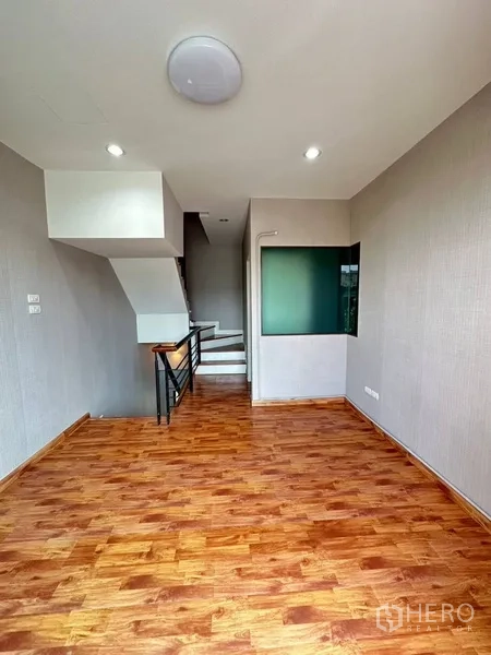 Townhouse for rent or sale in Phra Khanong, Bangkok - Upper-floor landing with glass corner window and stair handrail.