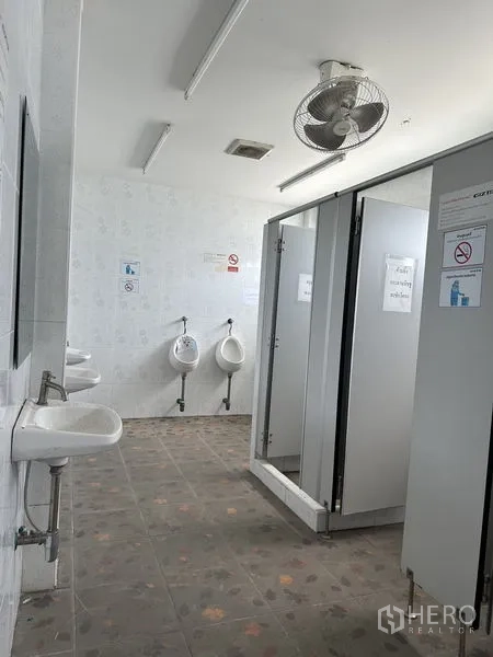 Warehouse for rent in Lat Krabang, Bangkok - Staff restroom with cubicles, urinals, sinks and a ceiling fan.