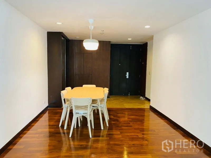 公寓 出租在Watthana, Bangkok - 餐区配六人餐桌与吊灯，木地板，靠近入户门。