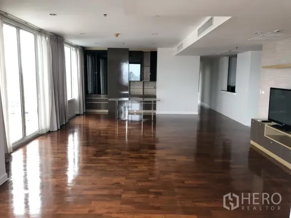 Condominium for rent in Khlong Toei, Bangkok - Open-plan lounge with floor-to-ceiling windows, glossy wood floors, and ample dining area space.
