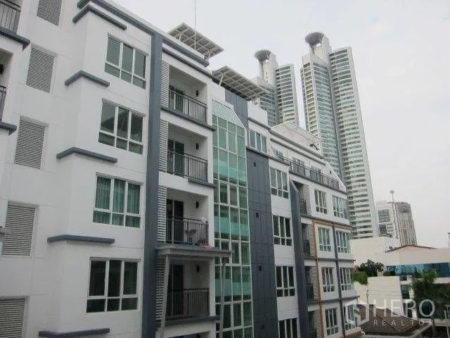 Condominium for rent in Khlong Toei, Bangkok - Exterior of a mid-rise condominium with balconies, set beside nearby high-rise towers.