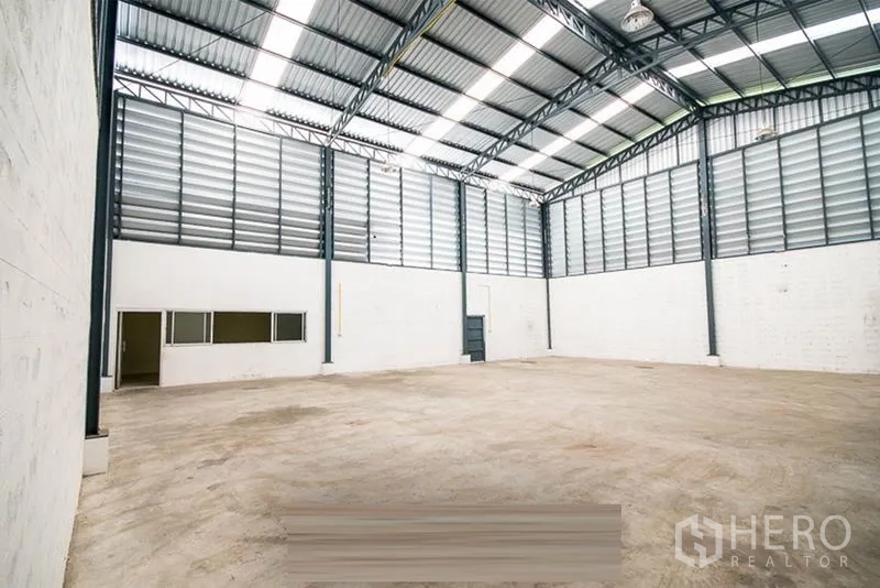 Warehouse for rent - Warehouse interior featuring a built-in office section and side access door.
