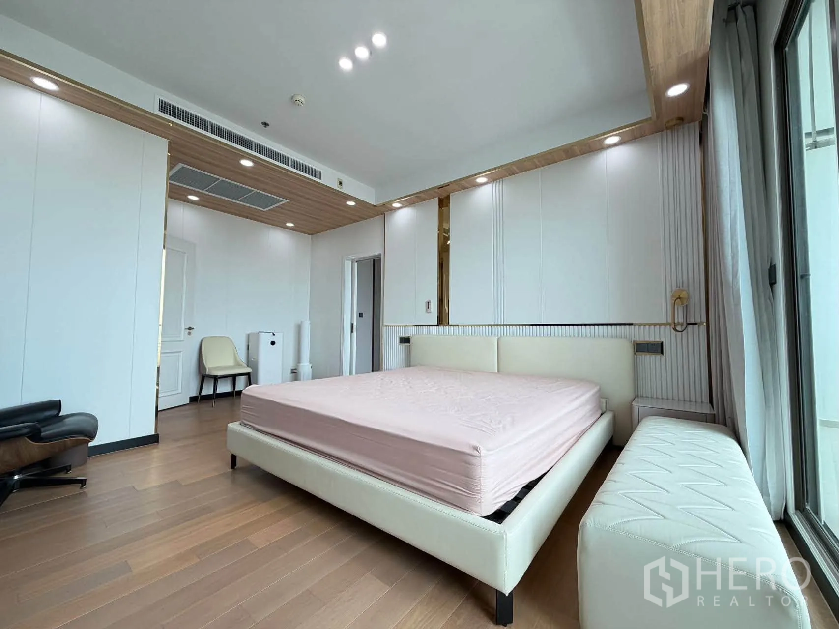 Condominium for sale in Watthana, Bangkok - Bright bedroom with upholstered bed, bench, and spotlights.