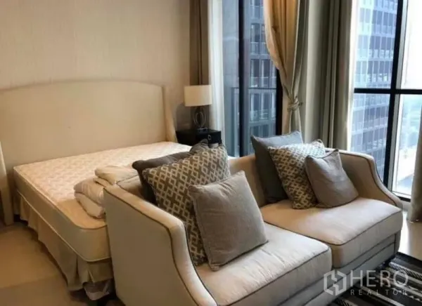 Condominium for rent in Pathum Wan, Bangkok - Bedroom with floor-to-ceiling windows offering a city view, a double bed, and a two-seat sofa.