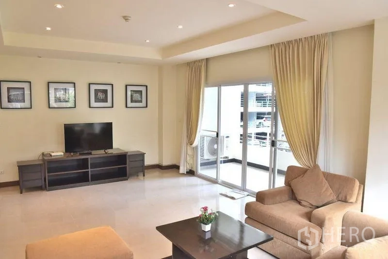 Apartment for rent in Sathon, Bangkok - Living room with TV unit and sliding doors opening to the balcony.